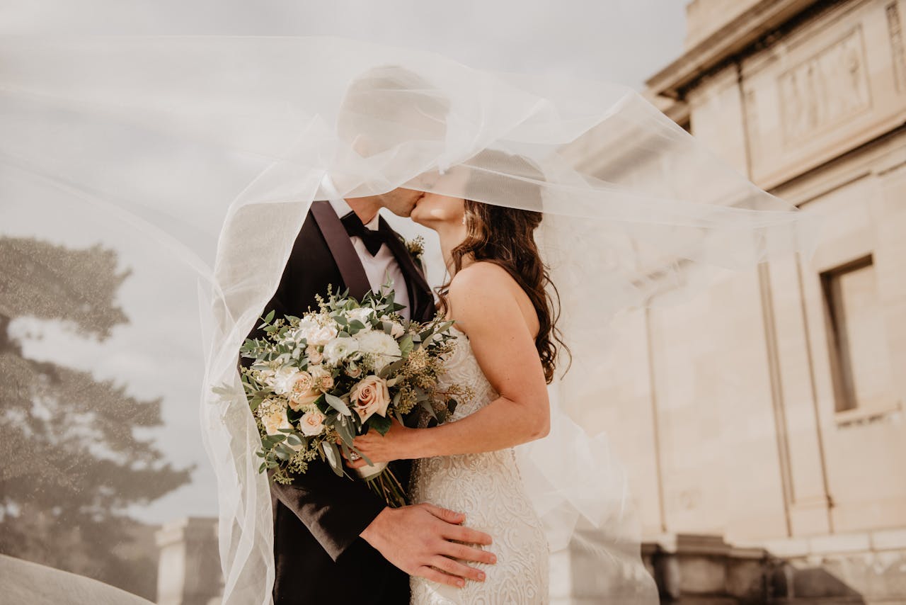 pexels-photo-2253870 Bride and groom share a tender kiss under a veil, showcasing love and romance on their special day.