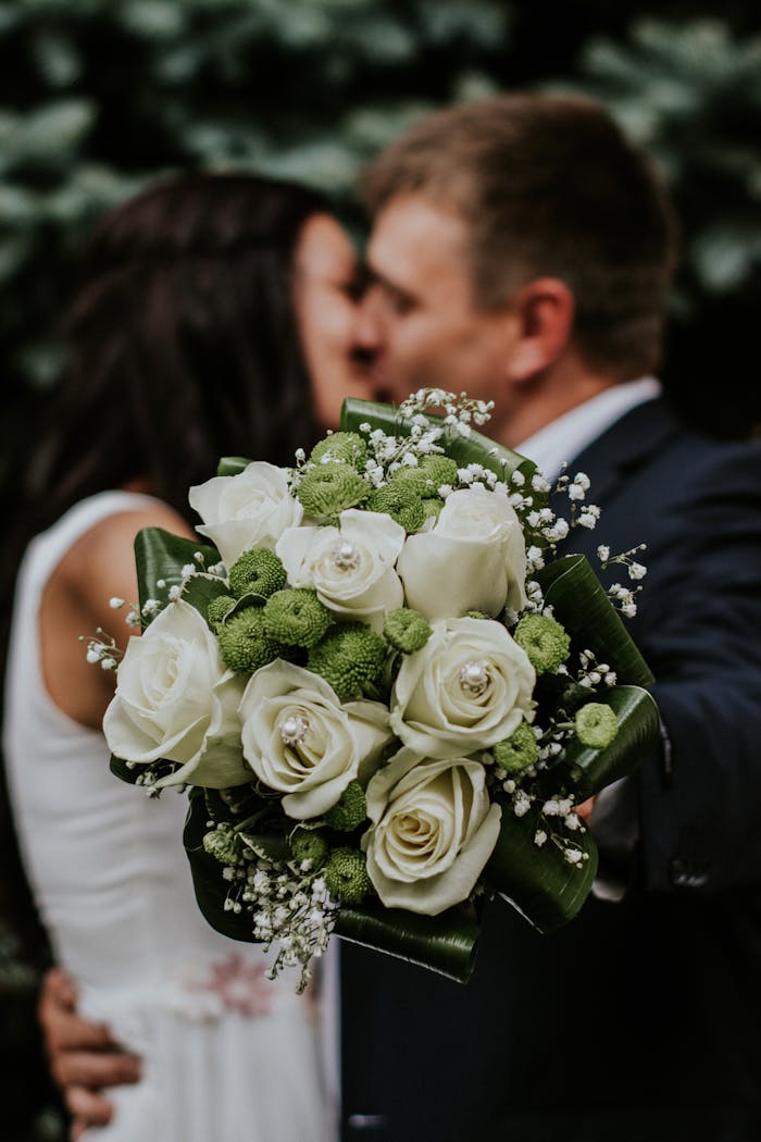 pexels-photo-948185 A couple embracing with a focus on a white rose and green floral wedding bouquet.